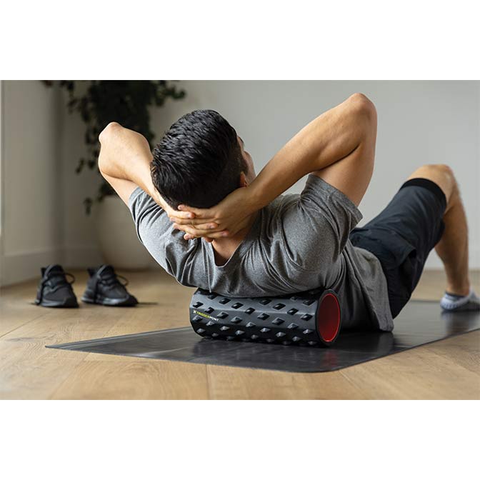 "A man in a home performing a deep-tissue self-massage on his back with the TriggerPoint CARBON™ Foam Roller."