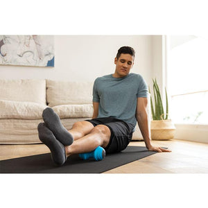 "A man in a home uses the the TriggerPoint™ CHARGE™ Vibe Vibrating Massage Roller" s vibration technology on his leg."