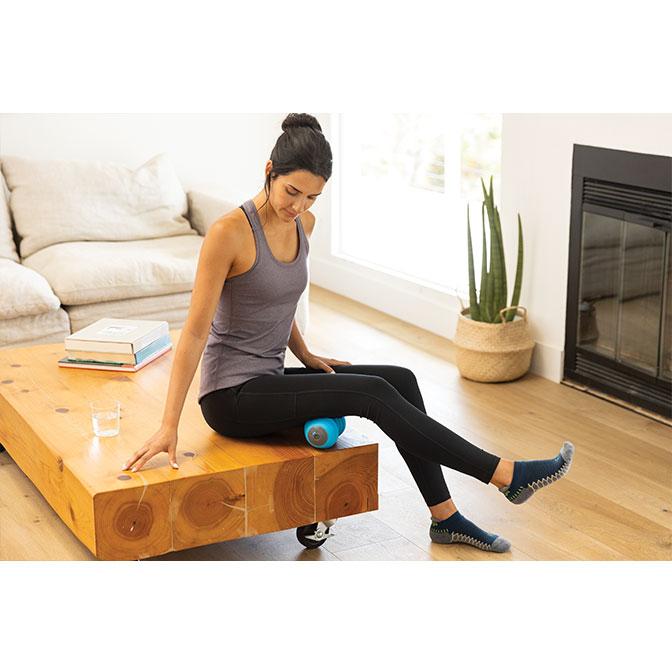 "A woman in a home uses the the TriggerPoint™ CHARGE™ Vibe Vibrating Massage Roller" s vibration technology on her leg.". 
