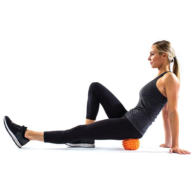 "A woman uses the TriggerPoint GRID Ball®" s compact design for targeted muscle pain relief in her hip.  