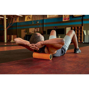 "A man in a gym uses the TriggerPoint GRID VIBE™ Plus vibrating foam roller" 